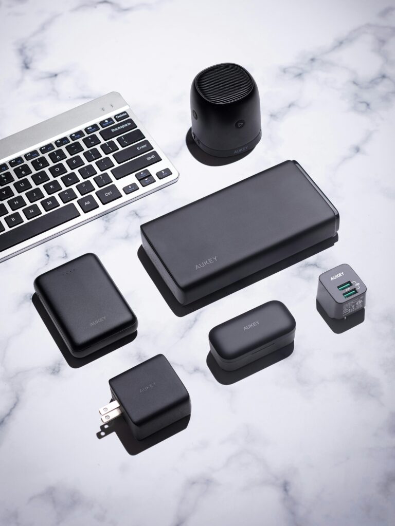 A collection of sleek black tech gadgets on a marble surface, featuring a keyboard and wireless speaker.
